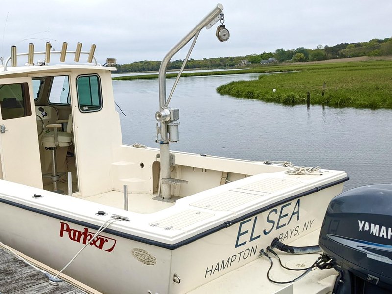 Navy blue boat lettering reading EL SEA with HAMPTON BAYS NY hailing port on the transom of a white Parker
