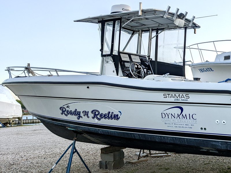 Navy blue script boat lettering reading Ready N Reelin alongside a Dynamic Financial Services business logo on a white Stamas hull