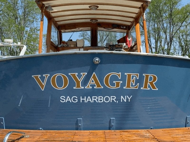 Gold serif boat lettering reading VOYAGER with SAG HARBOR NY hailing port on a navy blue transom